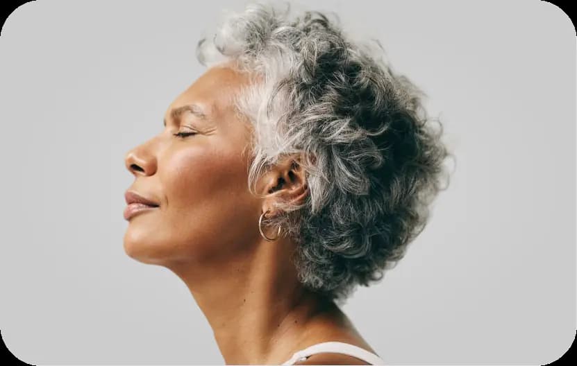 Mulher de cabelos grisalhos, de perfil e olhos fechados